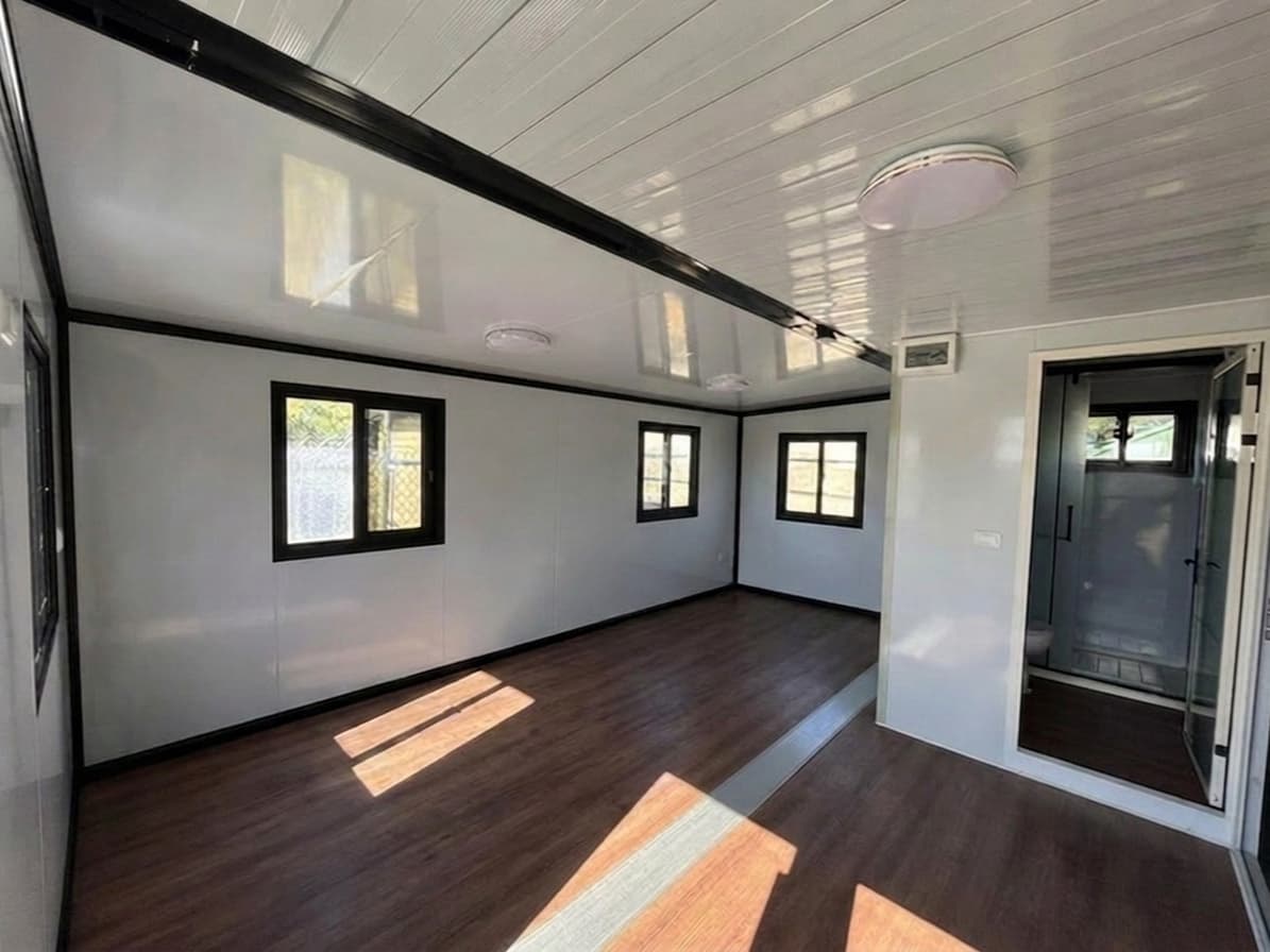Bare empty Expandable Home interior shell with wood-look flooring and the fitted bathroom pod.